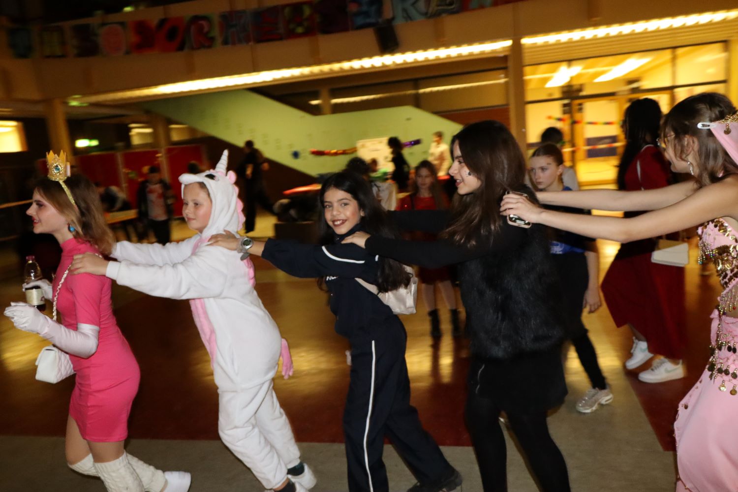 Kinder machen eine Polonaise durch die THRS Aula bei der Faschingsdisko