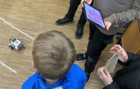 Schüler mit Ipads bedienen einen Lego Roboter bei thrs-go!