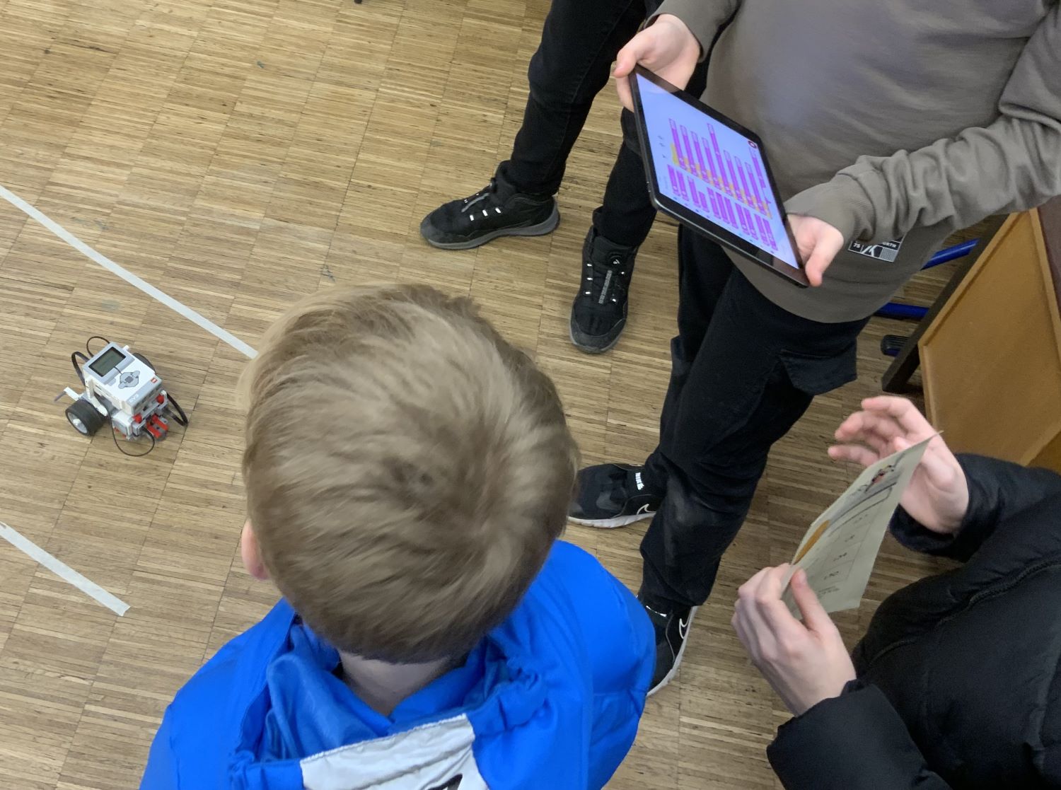 Schüler mit Ipads bedienen einen Lego Roboter bei thrs-go!