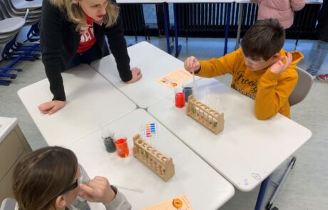 Zwei Schüler mit einer Lehrerin und Reagenzgläsern bei thrs-go!